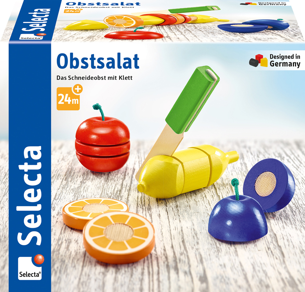 62020_Picknick_FS11_11_2019 Spielzeug-Schneideobst-Set mit Holzmesser und geschnittenen Obststücken auf einer „Obstsalat Selecta“-Schachtel.