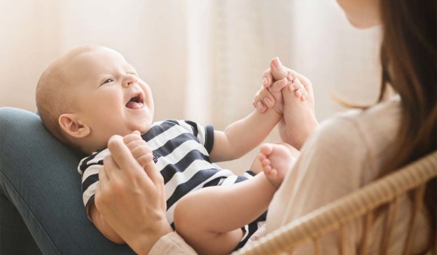 lachendes Baby auf dem Schoß einer Frau