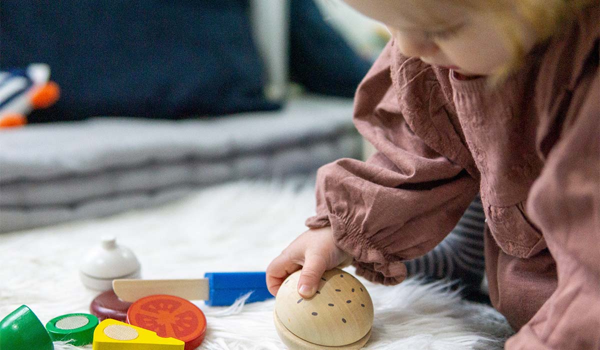 Kleinkind spielt mit Holz-Set Essen